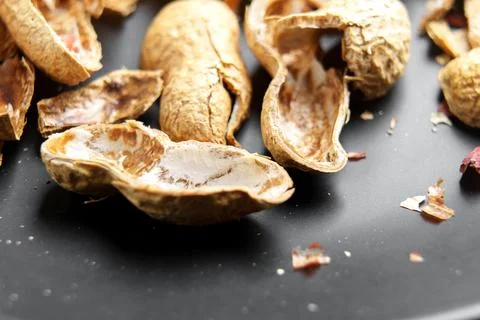 Empty shells of roasted peanuts on black ceramic plate. Macro. Foto stock