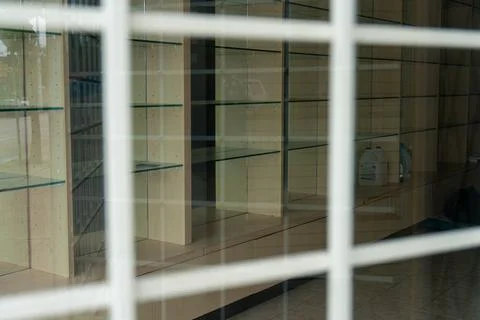 Empty shelves stand behind a white-barred window, awaiting new merchandise. Stock Photos