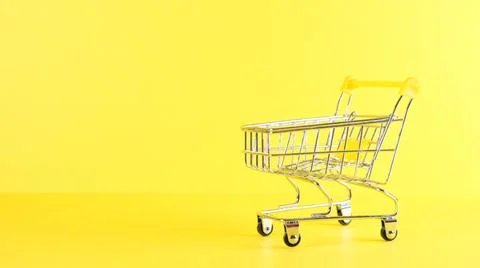 Empty Shopping cart on a yellow background, closeup. Black Friday Shopping and Stock Photos