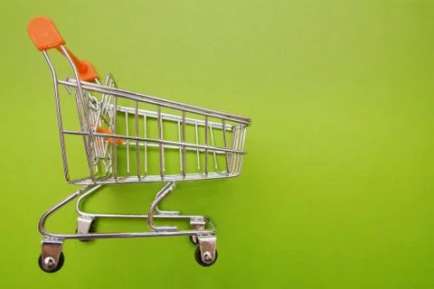Empty shopping trolley on green background with some copy space Stock Photos