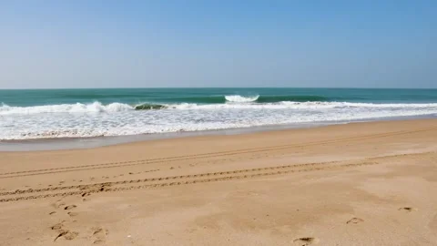 Empty shoreline with fresh tire tracks stretching across golden sand Stock Footage 332231515