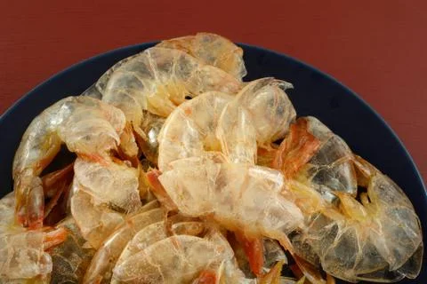 Empty shrimp shells stacked up on blue plate Stock Photos
