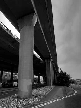 An empty sidewalk next to a huge concrete bridge Stock Photos