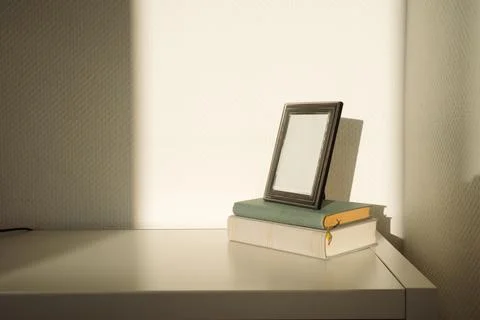 Empty silver photo frame on old books in direct sunlight Foto stock