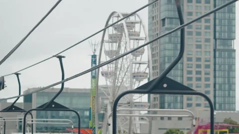 Empty Sky Ride Chairs and Ferris Wheel on an Urban Midway Stock Footage 343673114