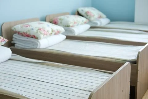 Empty sleeping area in kindergarten with neatly arranged beds and soft pillows Stock Photos