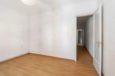 An empty small bright room with white walls and an open door overlooking a Фото