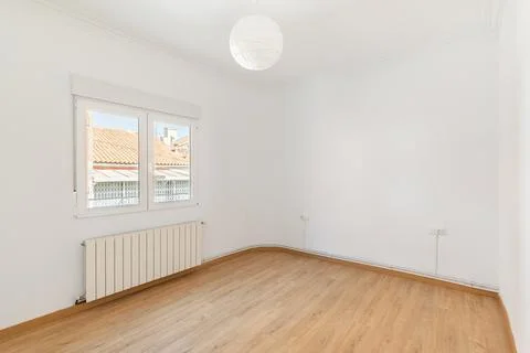 An empty small bright room with white walls and a window overlooking a neighbors 库存照片