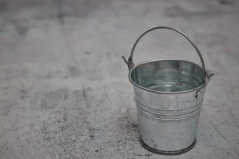 Empty small metal bucket isolated on a concrete background. copy space. horiz Stock Photos