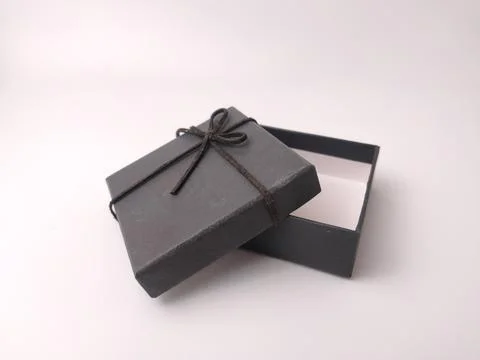 An empty small square black gift box sits with its lid propped open partial.. Stock Photos