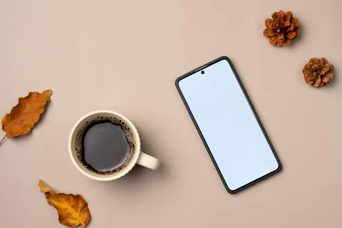 Empty smartphone screen with leaves, cone and cup of coffee on beige backgr.. Stock Photos