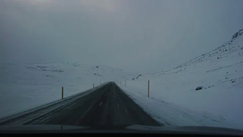 Empty snow-covered road under dramatic skies in Iceland's winter landscape Stock Footage 302346820