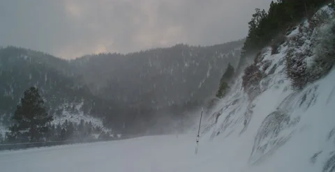 Empty snowy mountain road with blowing snow swirls from mountain top Stock Footage 219321019
