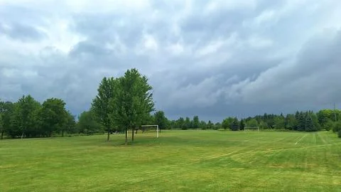 Empty soccer field under dark cloudy stormy sky Stock Photos