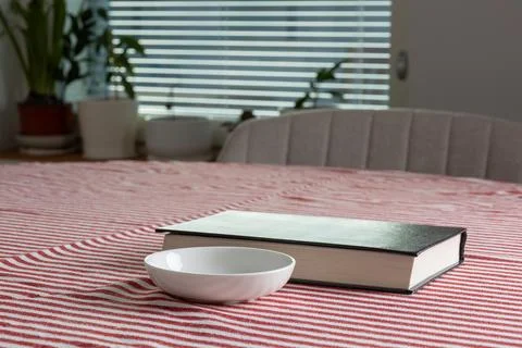 Empty space background. A book rests on a red striped tablecloth beside a w.. Stock Photos