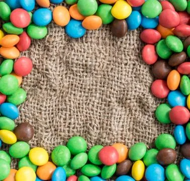 Empty space for text in a frame of colored candies.  textile background Stock Photos