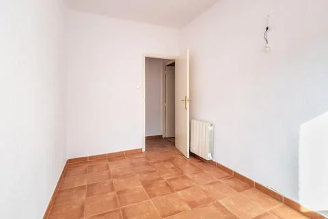 An empty spacious room with old square worn caramel colored floor tiles and a Stock Photos