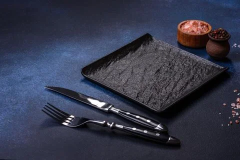 Empty square black plate on dark moody background with copy space Foto stock