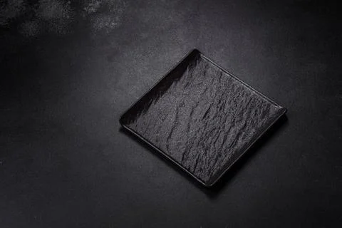 Empty square black plate on dark moody background with copy space Foto stock