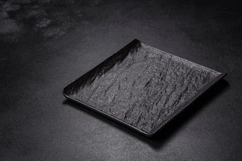 Empty square black plate on dark moody background with copy space Foto stock