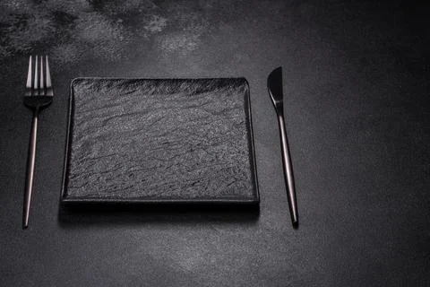 Empty square black plate on dark moody background with copy space Foto stock