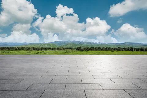 Empty square floor and green mountains under blue sky. Stock Photos