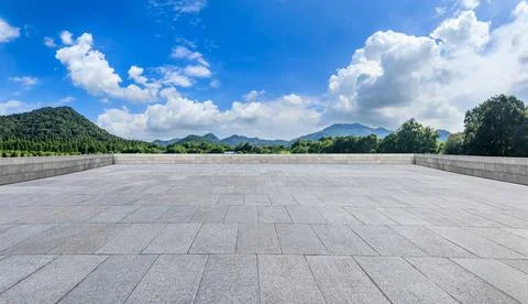 Empty square floor and green forest with mountain scenery under blue sky. Stock Photos