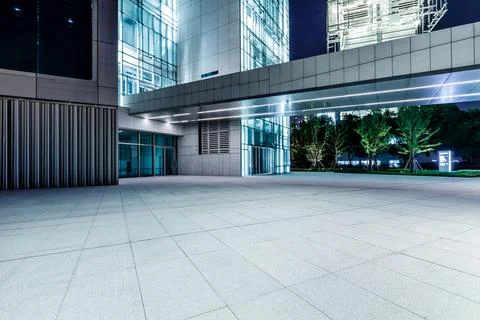 Empty square floor and modern commercial office building at night. Stock Photos
