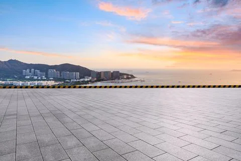 Empty square floor and modern city buildings with skyline by the sea. Stock Photos
