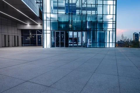 Empty square floor and modern commercial office building at night. Stock Photos