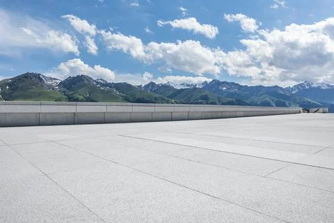 Empty square floor and mountains under blue sky. Stock Photos
