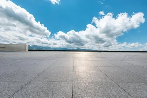 Empty square floor and mountains under blue sky. Stock Photos