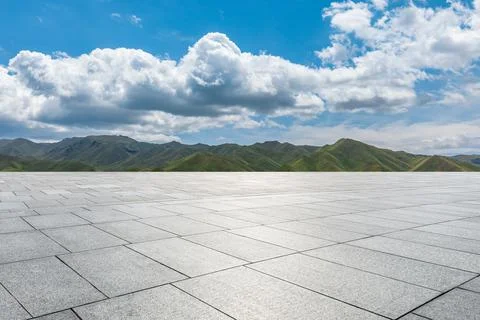 Empty square floor and mountains under blue sky. Stock Photos