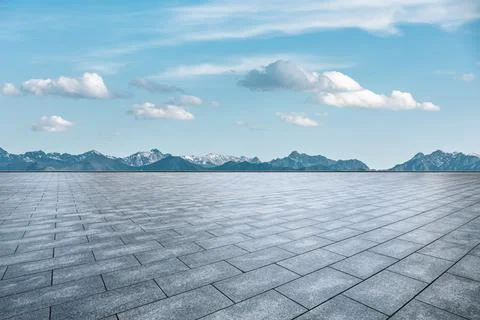 Empty square floor and mountains under blue sky. Stock Photos