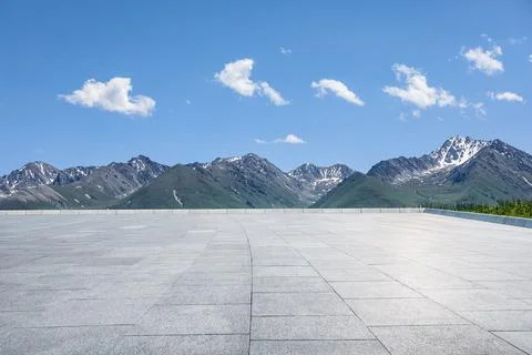 Empty square floor and mountains under blue sky. Stock Photos