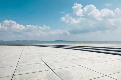 Empty square floor and river with mountains under blue sky. Stock Photos