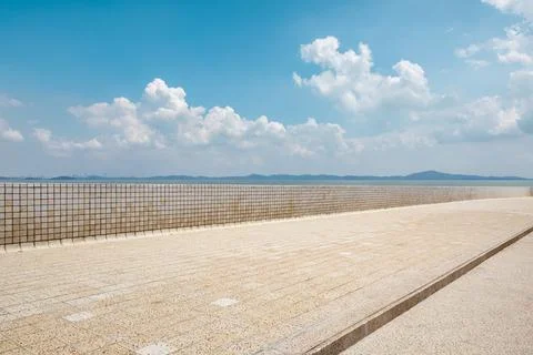 Empty square floor and river with mountains under blue sky. Stock Photos