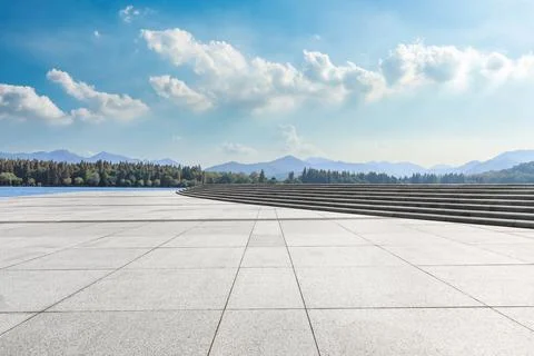 Empty square floor and river with mountains under blue sky. Stock Photos