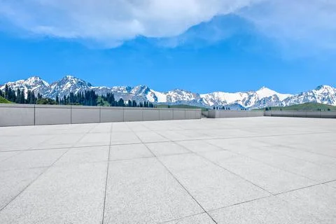 Empty square floor and snow mountains under blue sky. Stock Photos