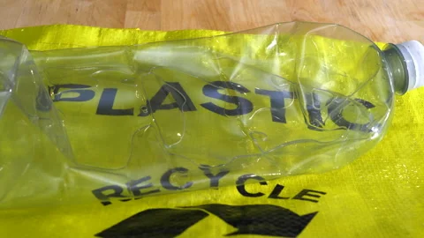 An empty squashed plastic bottle being placed on a recycling sack. Stock Footage 135305312