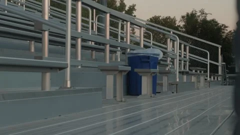 Empty stadium bleachers with blue recycling bin and slow right to left pan Video stock 338086766
