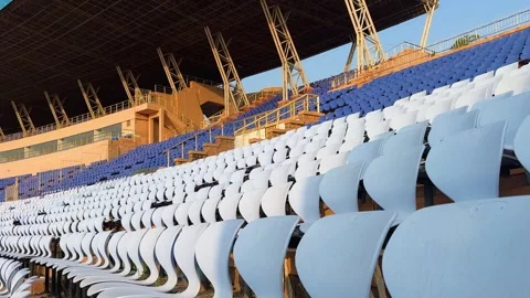 Empty stadium seating rows under morning light at sports arena Видео 321111480