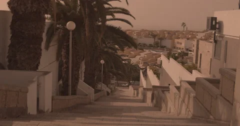 An empty staircase in Costa Adeje, surrounded by palm trees and hillside views Stock Footage 136136330