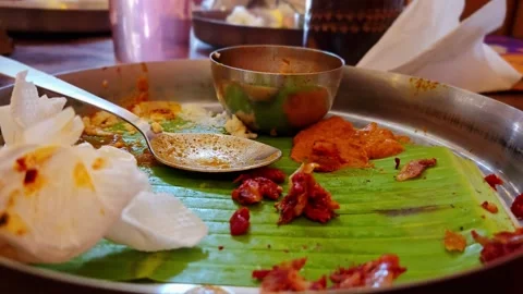 An empty steel platter with leftover scraps of a South Indian meal on a banana l 스톡 동영상 343756380