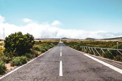 Empty straight road surrounded by dry landscape. Pespective from the middle of Stock Photos
