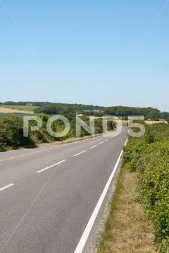 An empty straight road vanishing into the distance through attractive ...