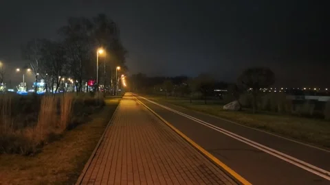 Empty street at night with lights along the path in a quiet area near a body of Stock Footage 325804187