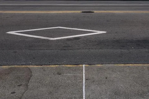 Empty street with a white diamond marking and cracked pavement on a sunny d.. Stock Photos