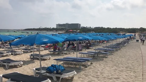 Empty Sun Beds and Umbrellas at the Beach with a Hotel at Background Stock-Footage 101249466