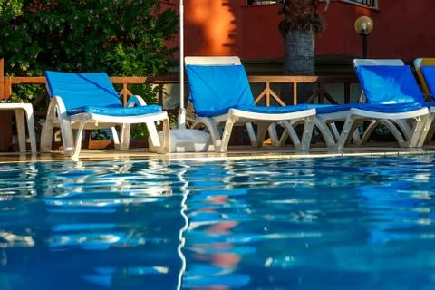 Empty sun beds on the edge of the pool Stock Photos
